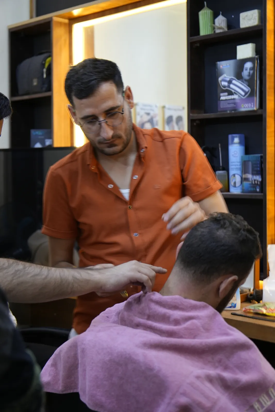 A barbering trainer teaching a student at Marka