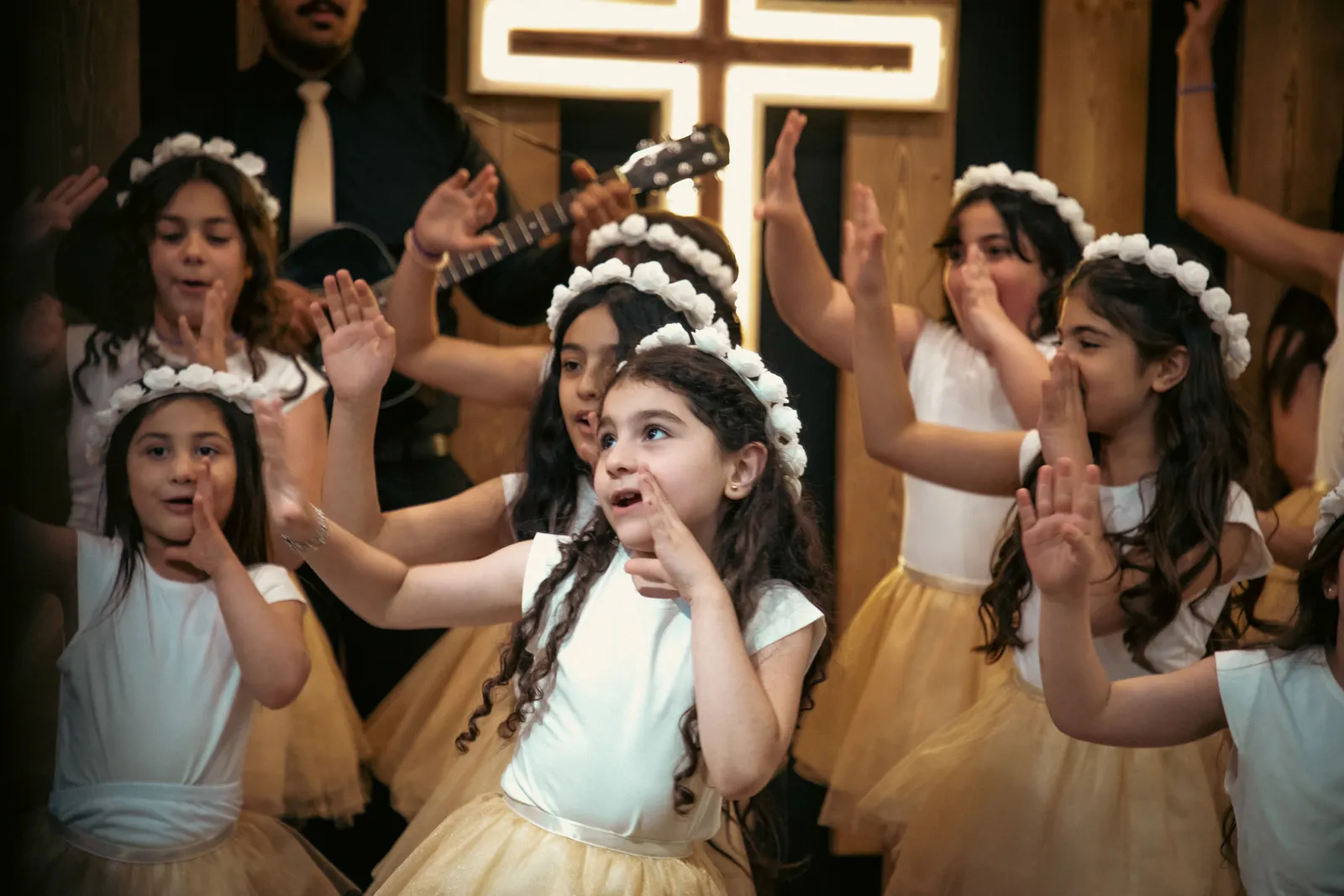 Girls in flower crowns worshipping beneath the cross at Marka Church