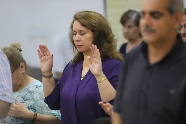 Women lifting their hands in prayer during a Marka course