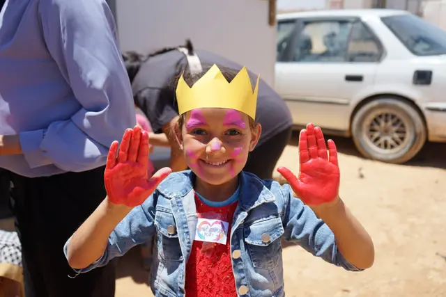 A smiling boy in a paper crown at a Mafraq children's day